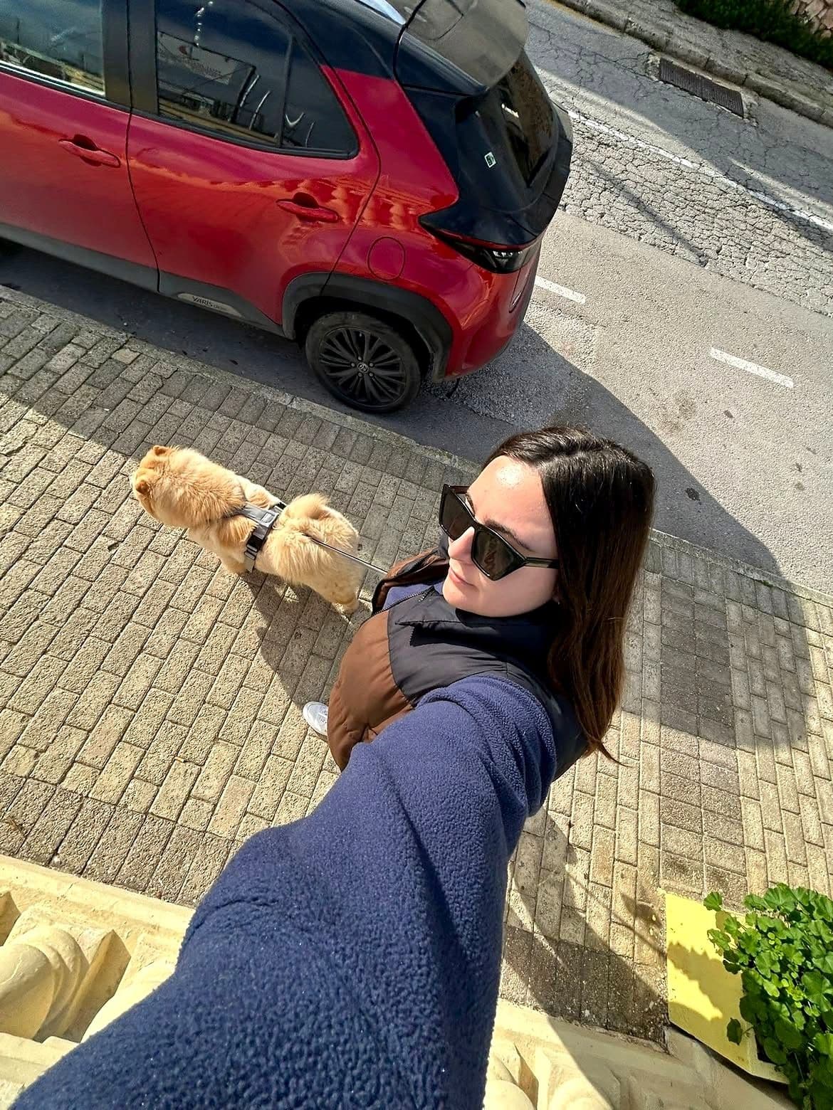 A sitter walking a happy dog through the streets of Malta
